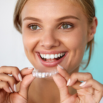 A patient putting on their SureSmile Clear Aligners